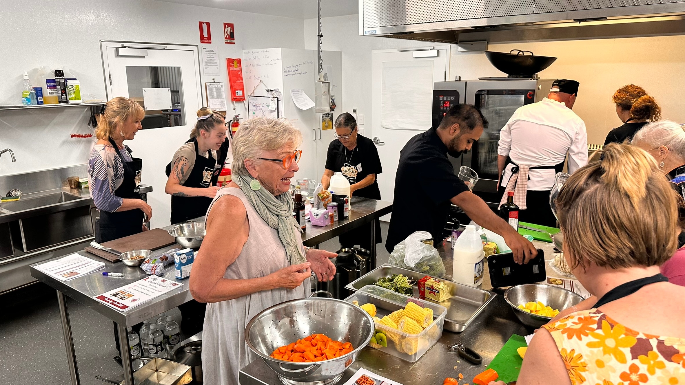 People make food in a commercial kitchen.