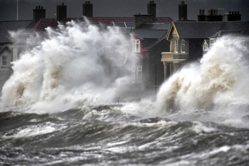 Wind gusts from a "weather bomb" have battered parts of the UK causing huge swells in coastal areas.