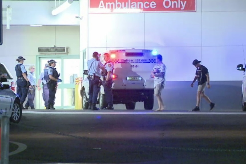 Police officers gather in a hospital car park.