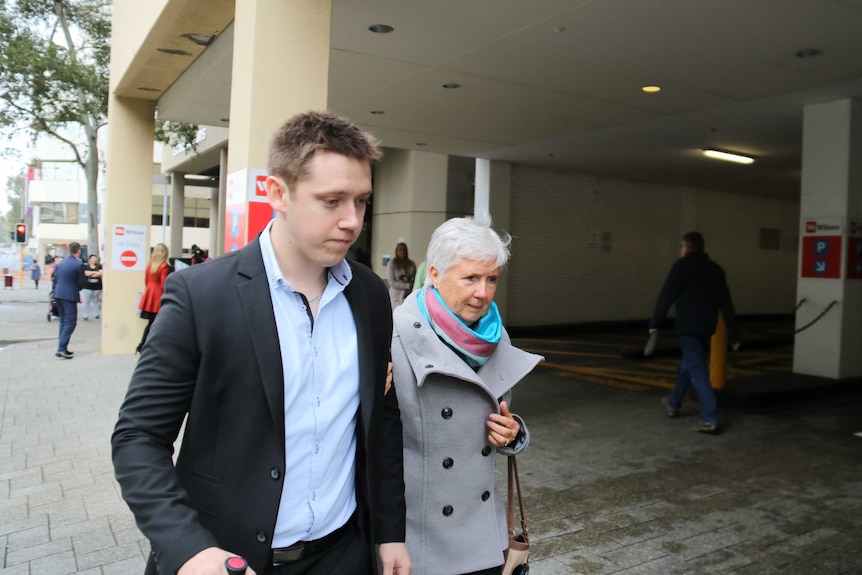 Nicole Bicknell's boyfriend Jason Roberts walks outside court with an older woman holding his arm.