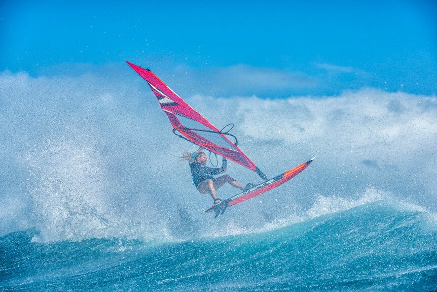 An action shot of a windsurfer riding a wave