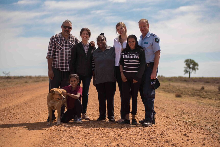 Actors and director, Imogen Thomas, stand on dirt road at Brewarrina.