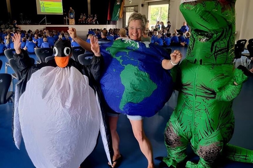 Marji and her two boys giving a talk in Queensland dressed as a globe, a dinosaur and a penguin
