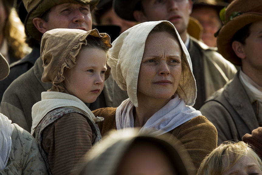 Colour still of Maxine Peak carrying Alicia Turner while standing amongst crowd of protestors in 2018 film Peterloo.