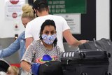 People wearing face masks are seen in the baggage collection area.