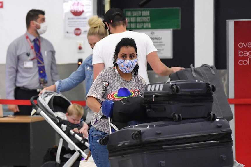 People wearing face masks are seen in the baggage collection area.