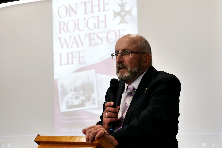 Photograph of a man at a podium with an image projected behind him