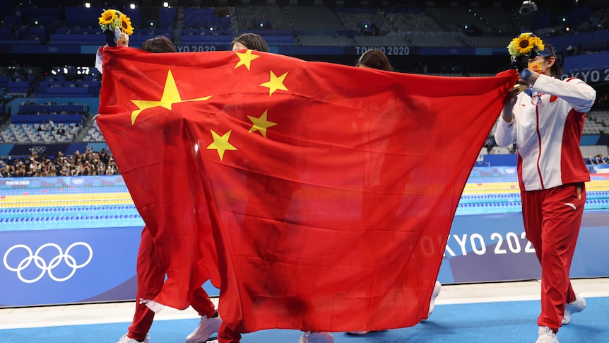 A Chinese flag is held up poolside by unidentifiable members of Team China