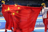A Chinese flag is held up poolside by unidentifiable members of Team China