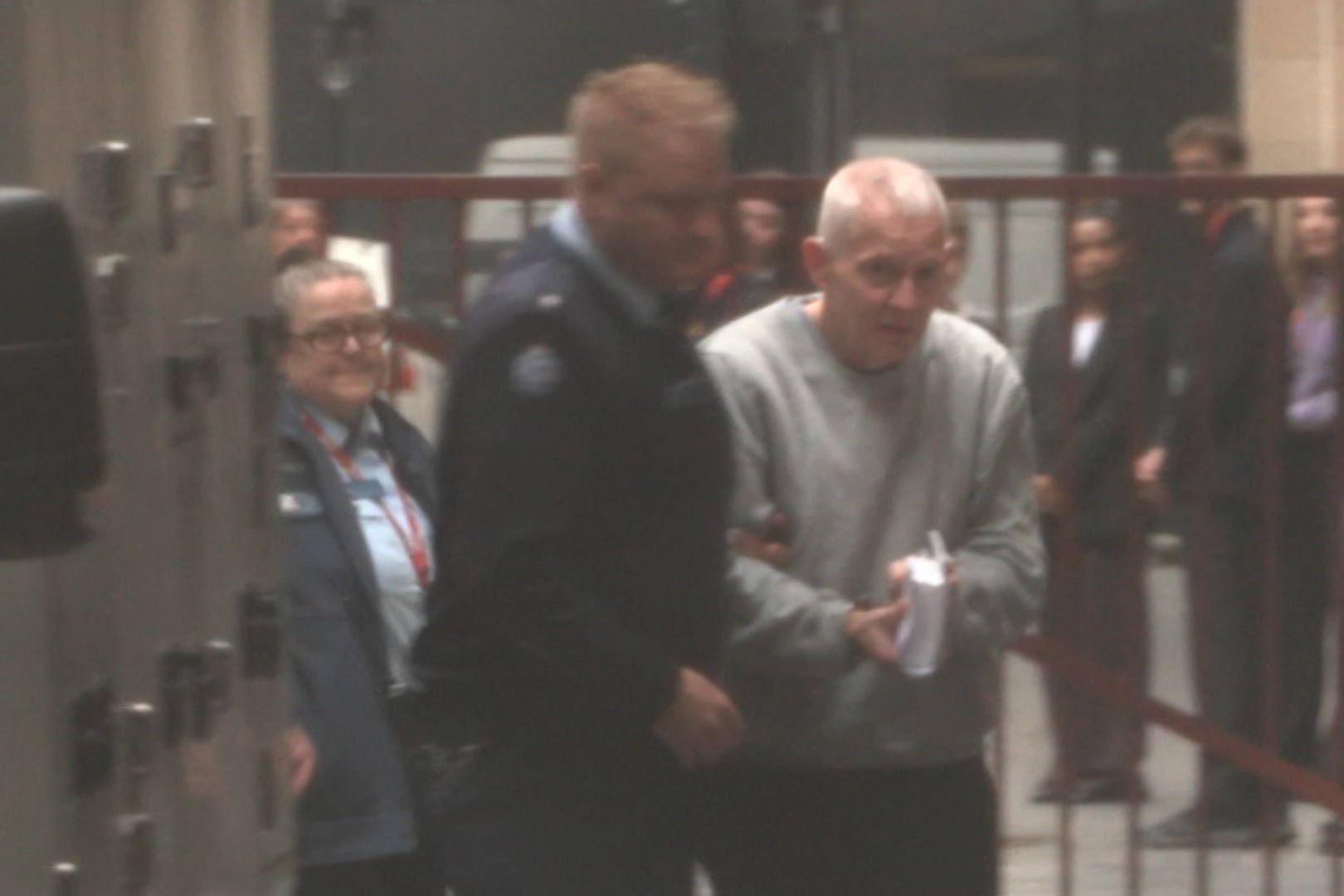 A man being led into court from a prison van.