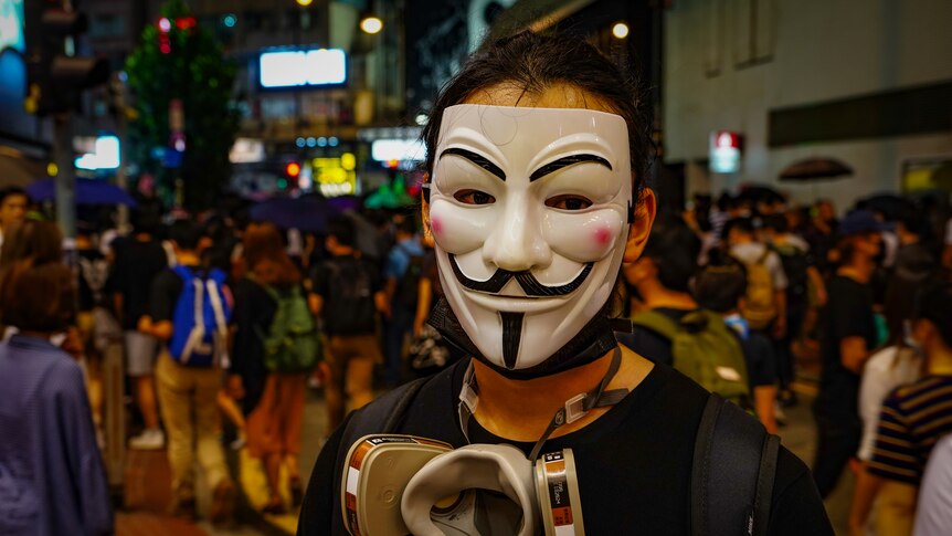 A protester hides his face behind a Guy Fawkes mask