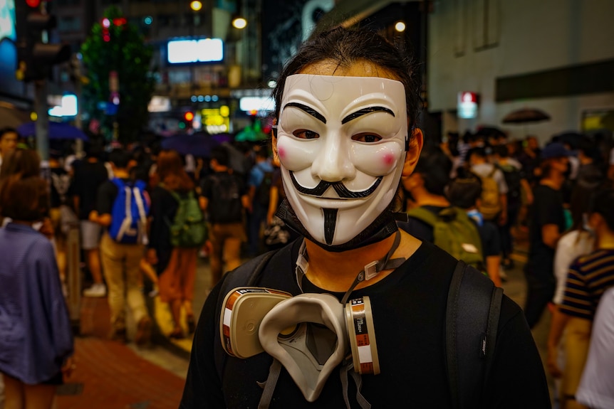 A protester hides his face behind a Guy Fawkes mask