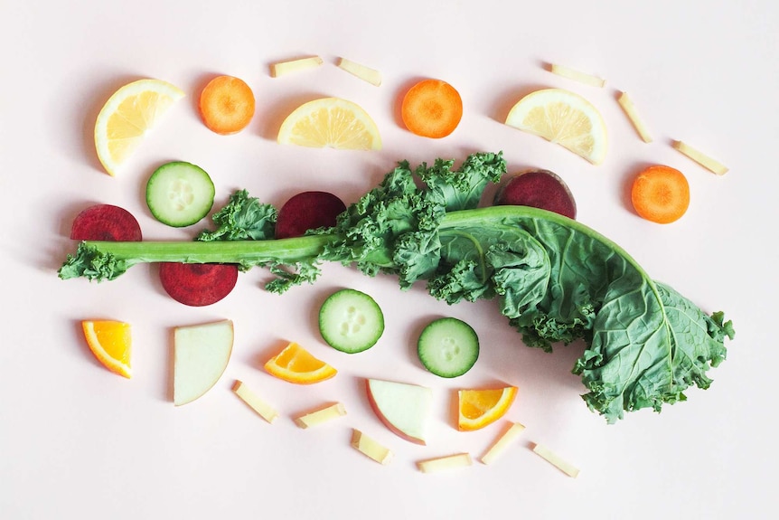 Flatlay of nearly organised sliced carrot, lemon, beetroot, apple, kale and ginger.