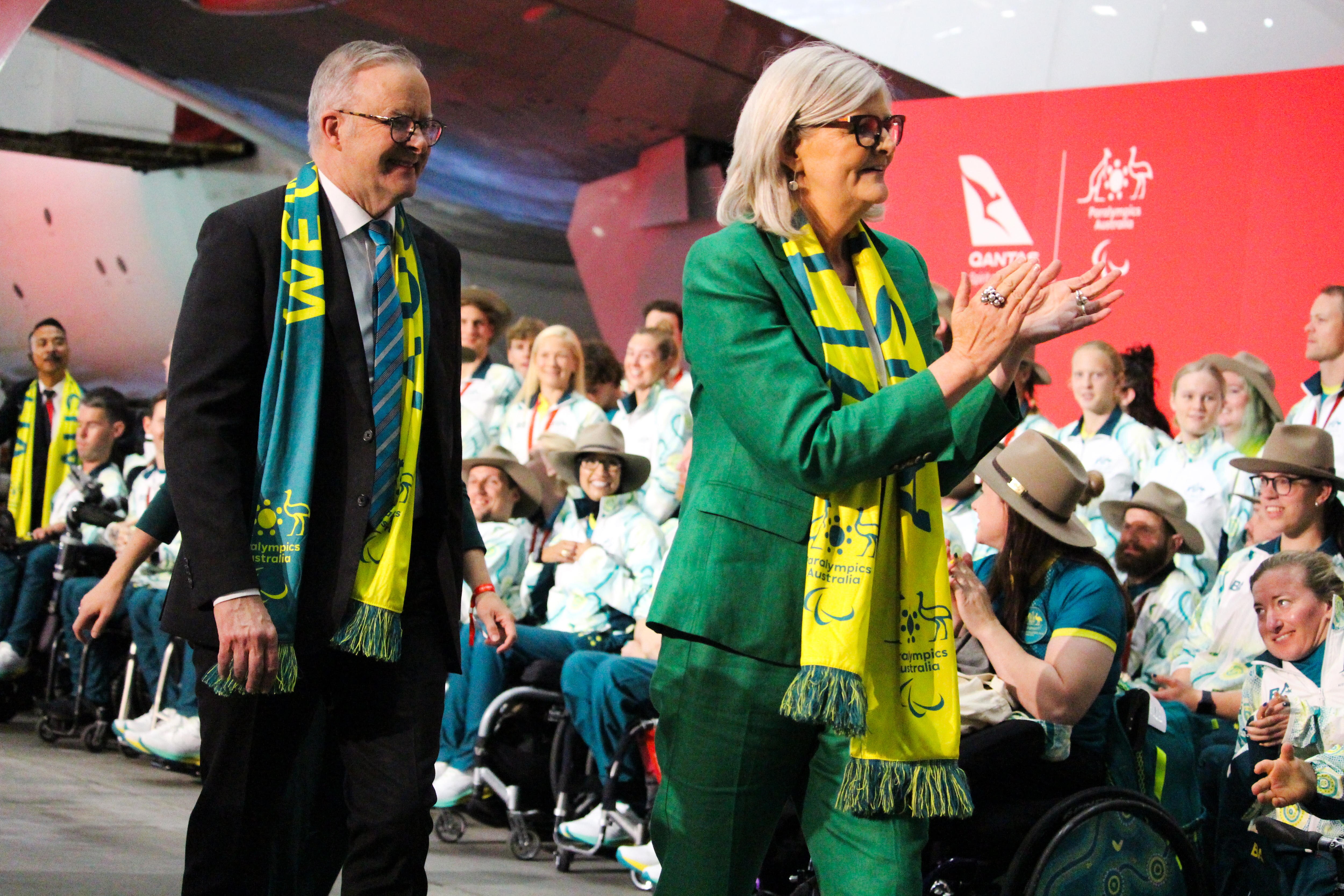 Two older people welcoming athlete's in front of a plane