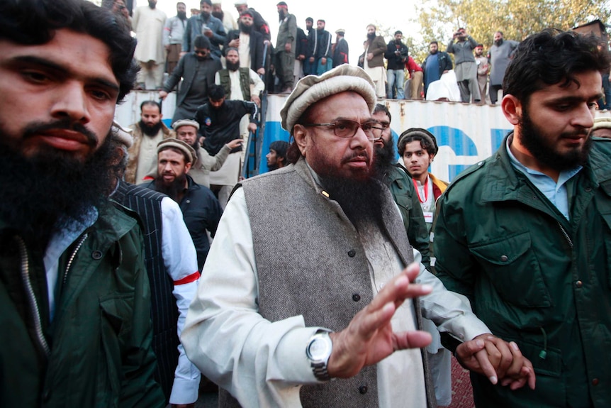 Hafiz Saeed walks among a group of men.