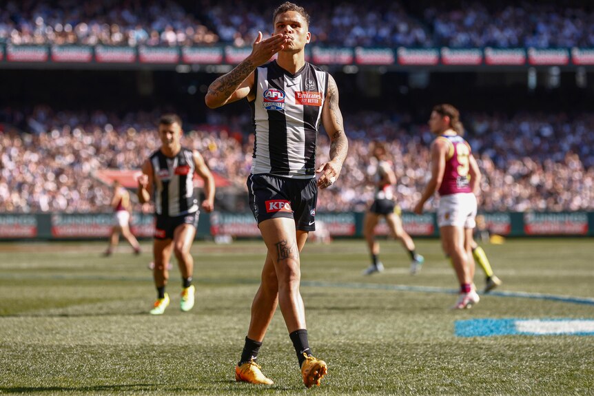 A Collingwood AFL player kisses his hand as he celebrates a goal in the grand final against the Brisbane Lions.