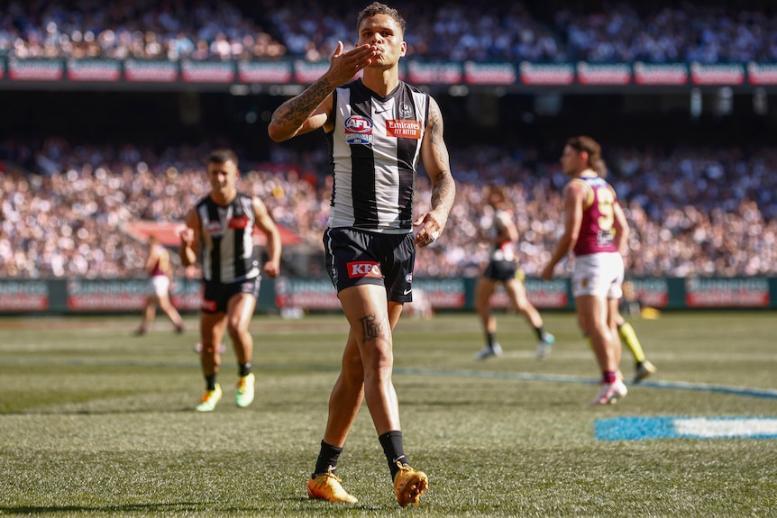 A Collingwood AFL player kisses his hand as he celebrates a goal in the grand final against the Brisbane Lions.