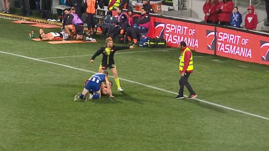 A security guard is sent away from two players on the pitch after he rushes over to help separate them