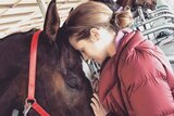 Hollywood actress Teresa Palmer touches heads with a horse.