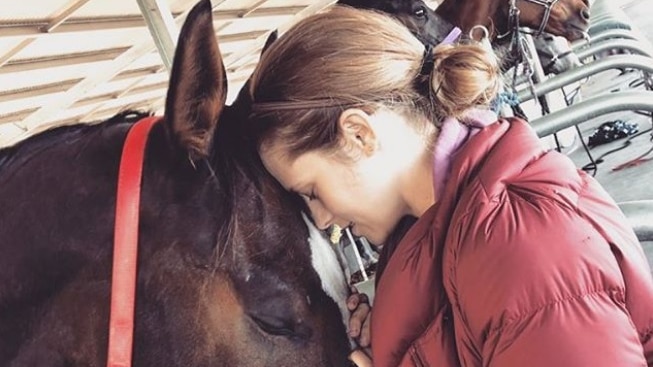 Hollywood actress Teresa Palmer touches heads with a horse.