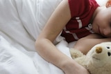 A child is asleep with a teddy.