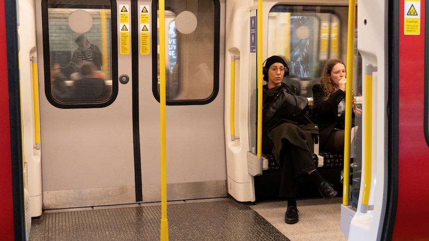 People sitting wearing earphones on London's Tube.