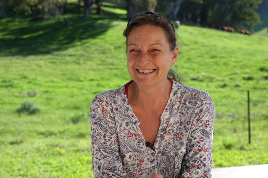 Portrait of Birgit smiling with a green paddock in the background.