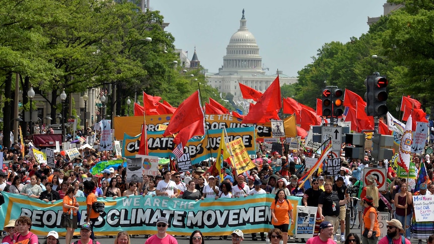 People march carrying signs reading "we are the people's climate movement".
