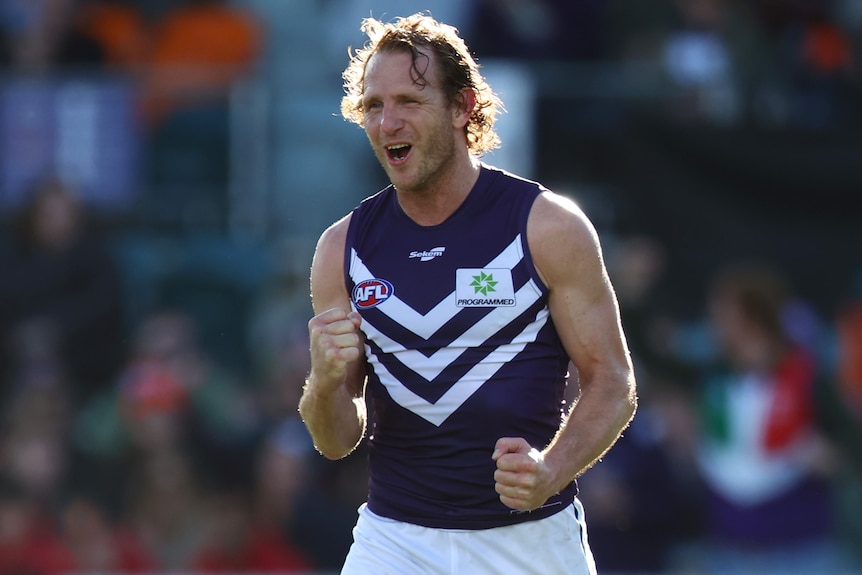 A Fremantle Dockers AFL player pumps his fist as he celebrates a goal.