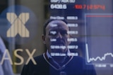 Pedestrians are reflected in a window with an indicator board displaying stock prices at the Australian Stock Exchange in Sydney
