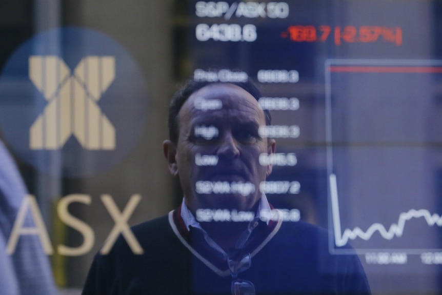 Pedestrians are reflected in a window with an indicator board displaying stock prices at the Australian Stock Exchange in Sydney