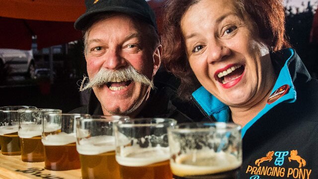 A woman and a man smile over pints of beer.