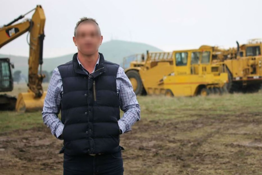 Man stands in front of excavating equipment
