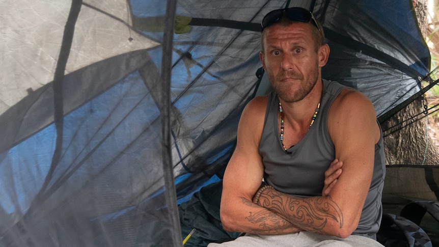 man in singlet sitting inside tent