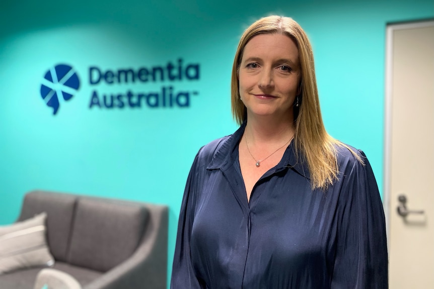 A woman standing in front of a Dementia Australia sign
