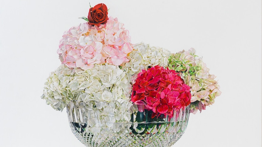 A crystal glass with hydrangea flowers in it arranged to look like an ice cream sundae.