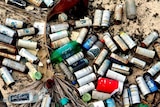 A pile of spent spray cans discarded on a beach.