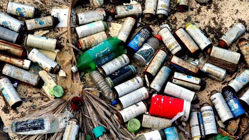 A pile of spent spray cans discarded on a beach.