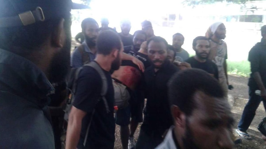 Men carry a man reportedly shot in Port Moresby, PNG.