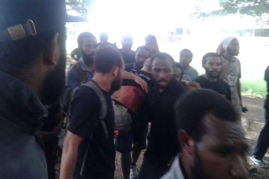 Men carry a man reportedly shot in Port Moresby, PNG.