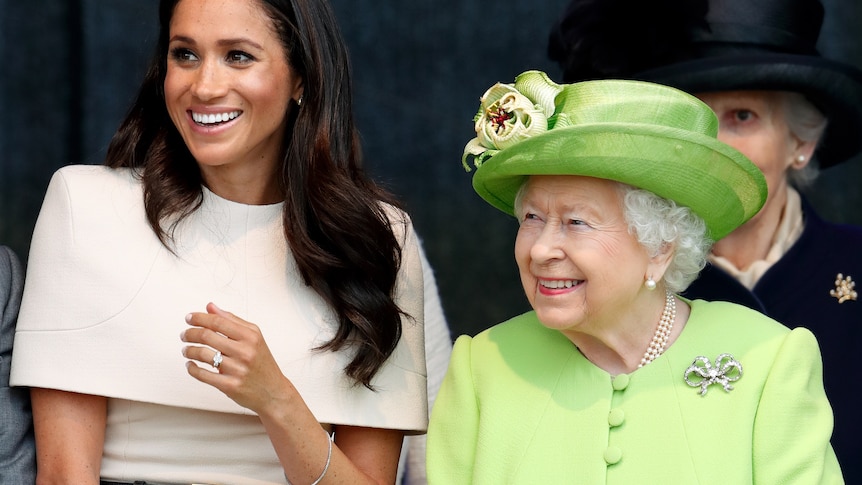Megan, Duchess of Sussex, wearing beige, and Queen Elizabeth, wearing lime green, sit and smile together