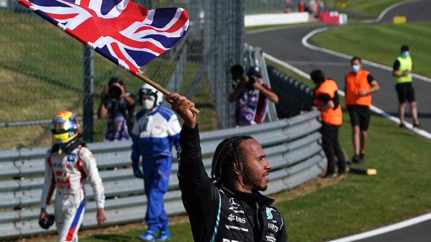 Driver holding a Union Jack flag celebrating with the crowd.