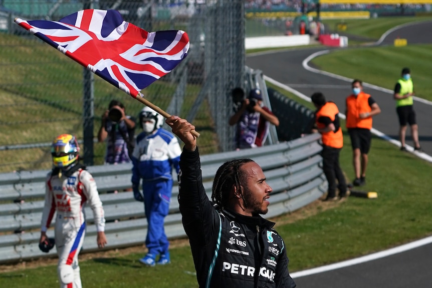 Driver holding a Union Jack flag celebrating with the crowd.