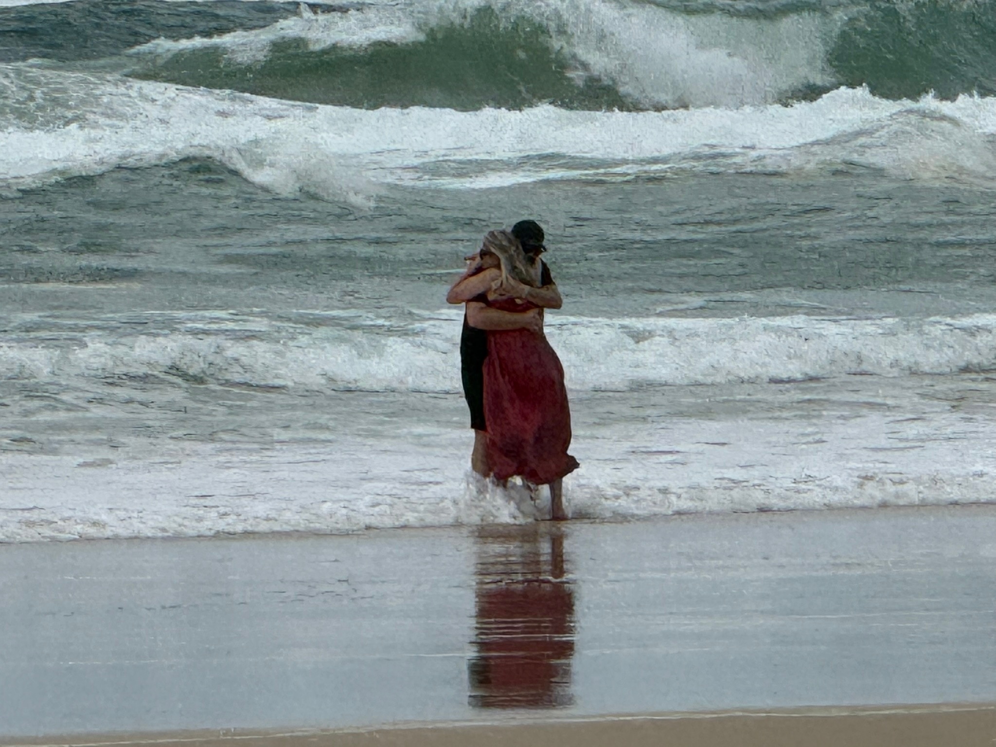 A couple embrace at the ocean's edge.