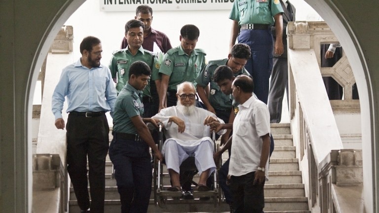 Ghulam Azam is assisted by security personnel