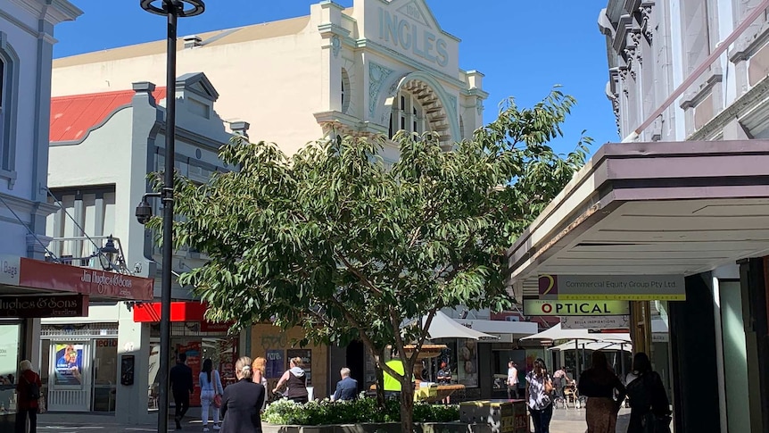 A pedestrian mall with an old building facade that reads 'Ingles' in the background.