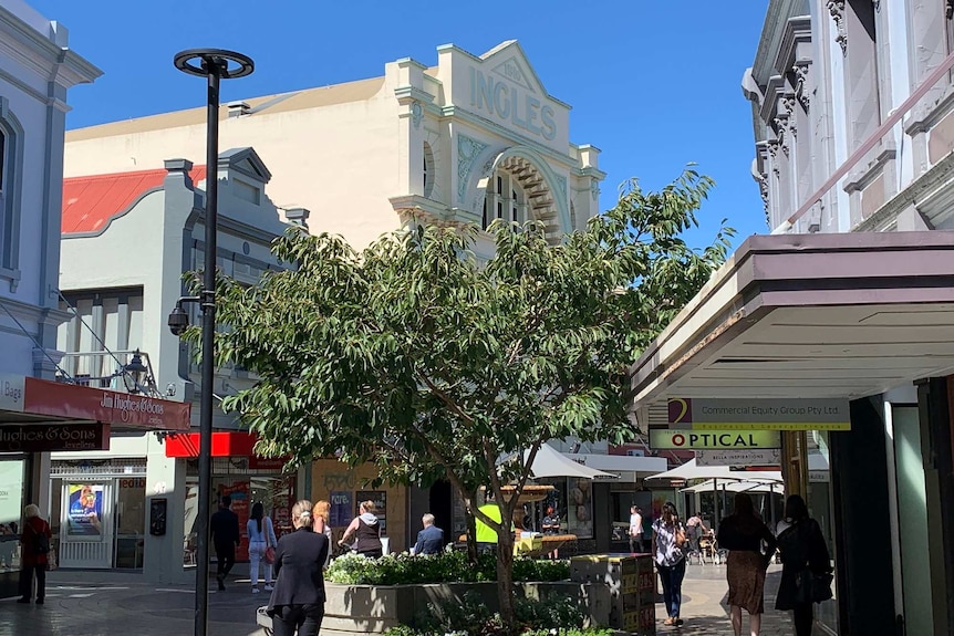 A pedestrian mall with an old building facade that reads 'Ingles' in the background.