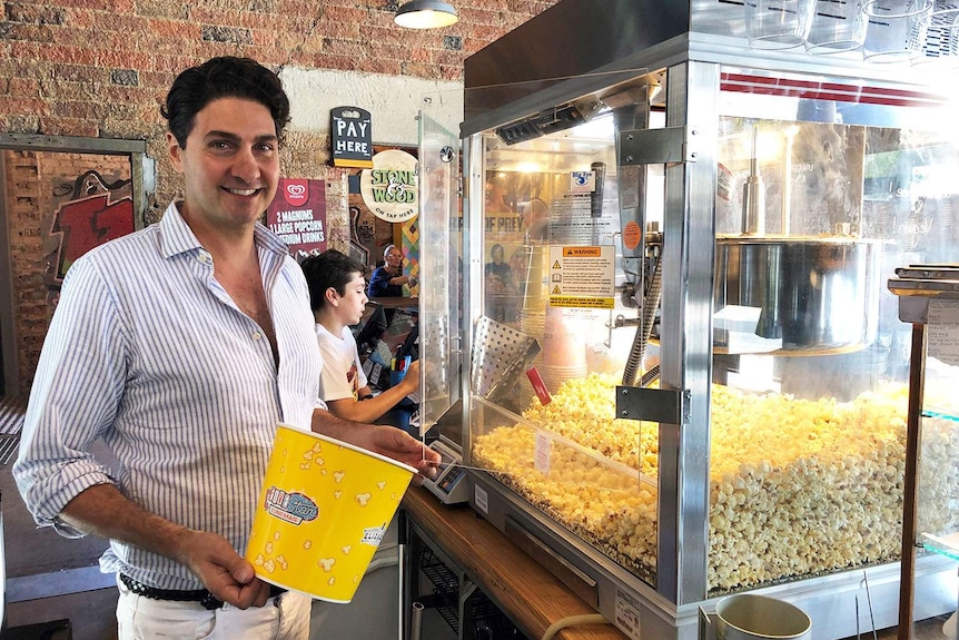 Red Hill Cinema operator Stephen Sourris fills a container with popcorn at the complex in Brisbane.