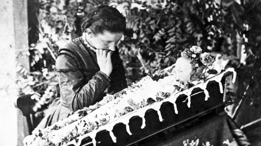 Child in a coffin with a grieving mother