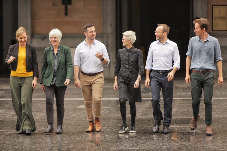 Greens MPs walk in a line smiling and talking.